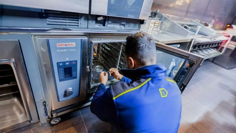An Aspect commercial gas engineer repairing an oven in a commercial kitchen.