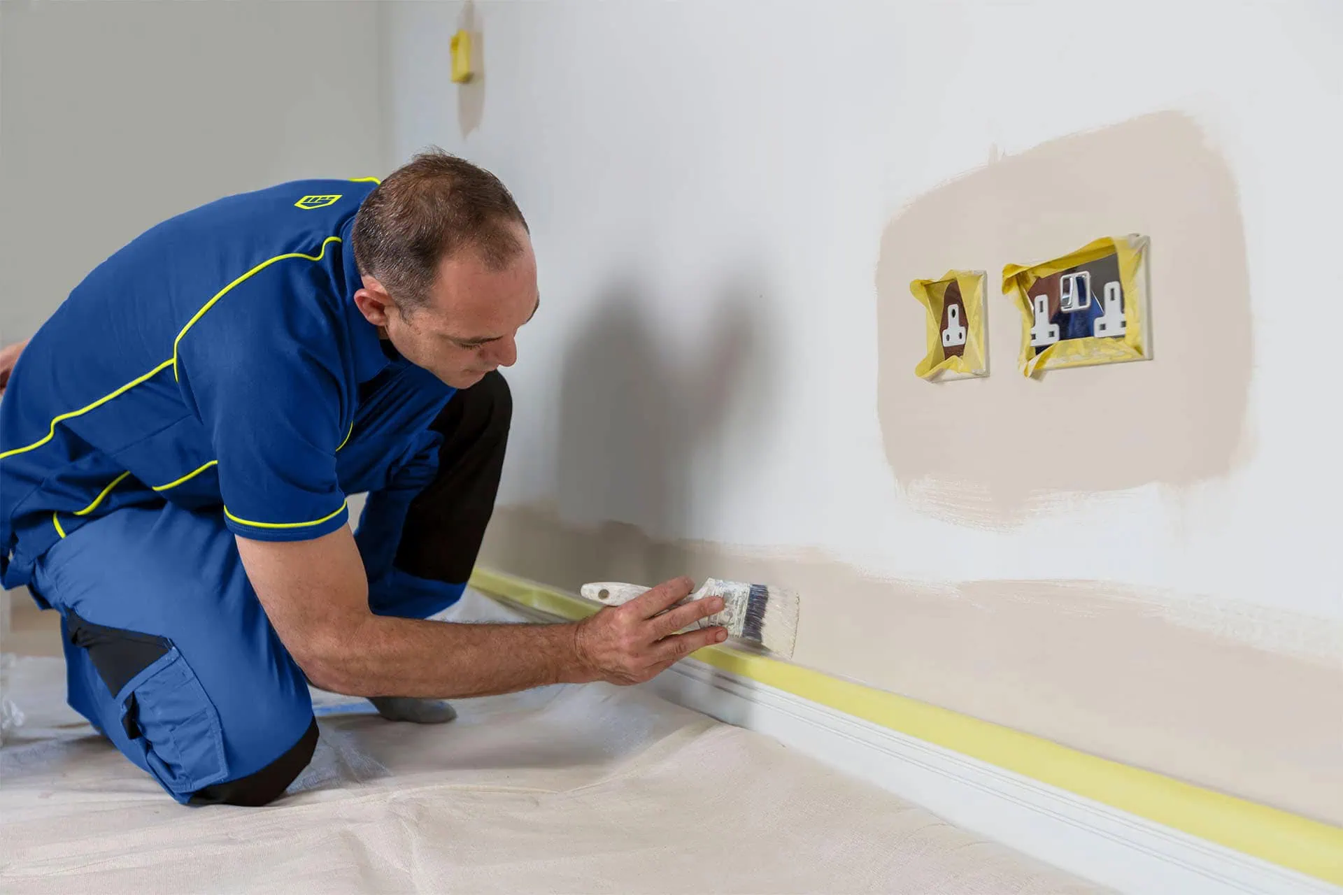 An ASpect painter decorator cutting in along skirting board and around electrical sockets.